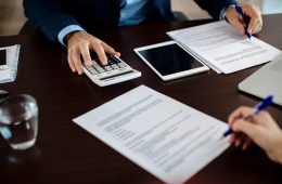 Close-up of real estate agent calculating costs of a mortgage agreement while having a meeting with a client in the office.